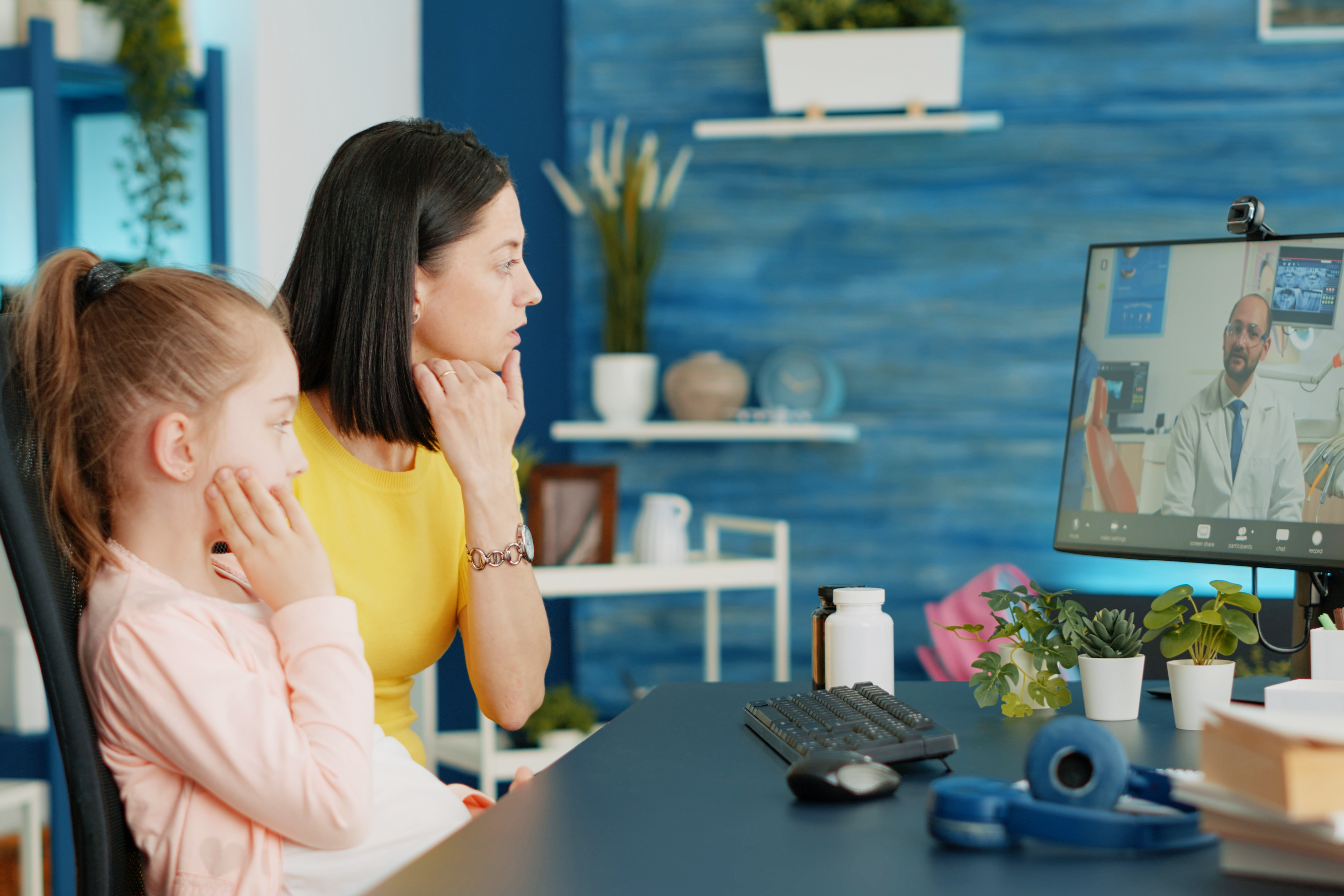 Mother of girl with toothache talking to dentist on video call for oral care advice and treatment to cure pain. Parent using online conference for remote consultation and telemedicine.