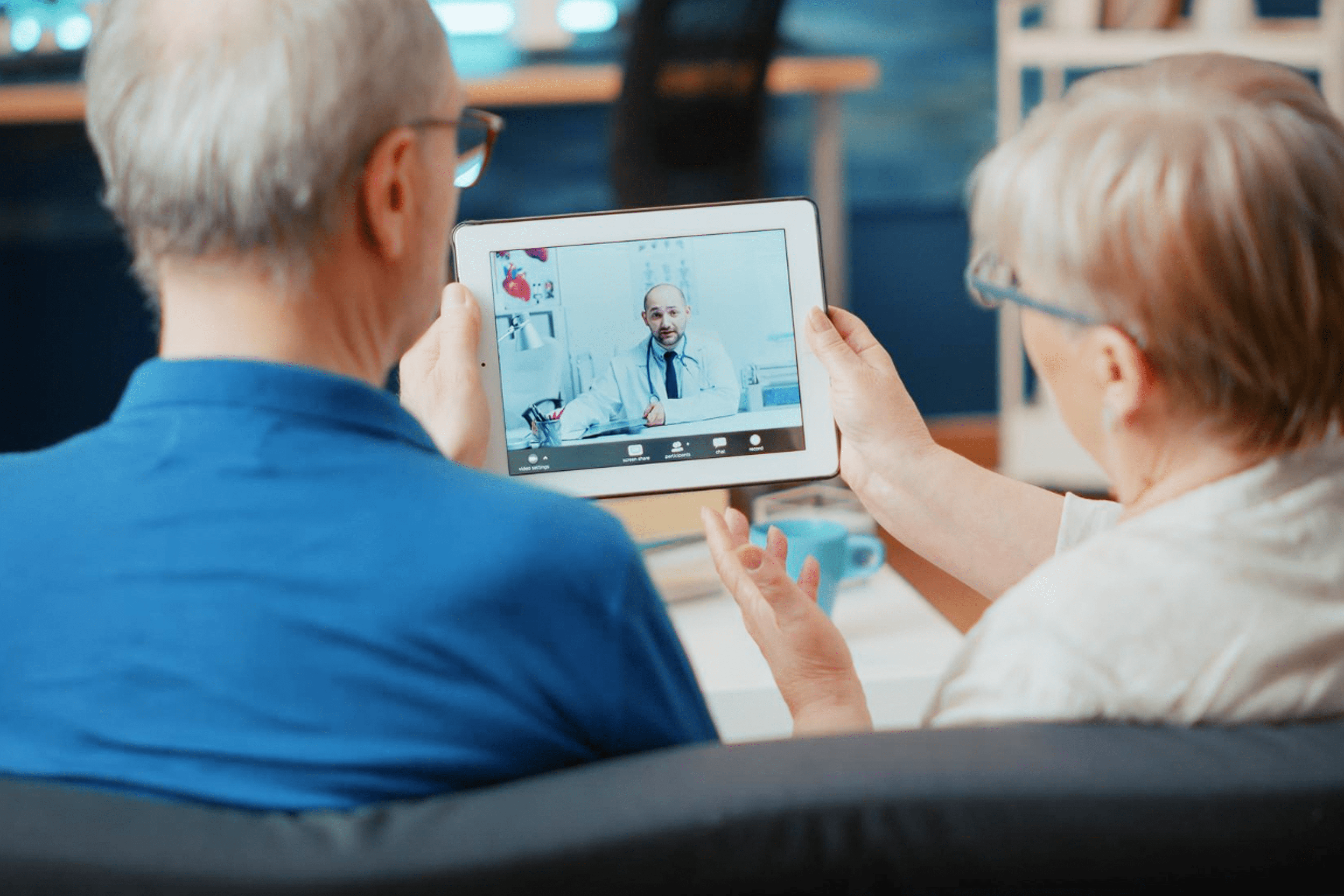 Old couple closely looking at their tablet taking to a doctor during a virtual consultation.